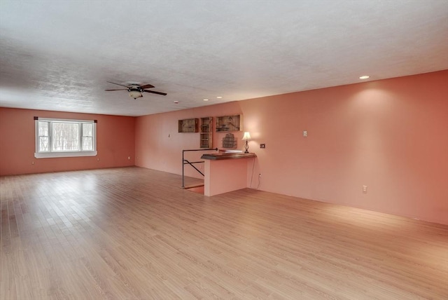 unfurnished living room featuring a textured ceiling, ceiling fan, and light hardwood / wood-style flooring