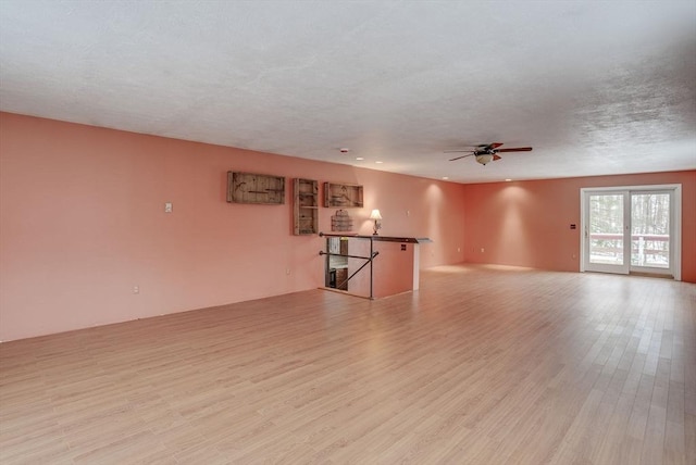 empty room featuring ceiling fan, light wood-type flooring, and a textured ceiling