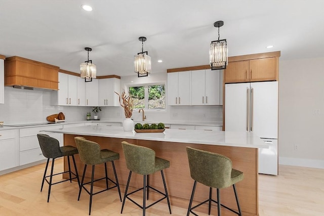 122 Charles St, Reading, MA 01867 - kitchen with white fridge, a center island, backsplash, a chandelier, and light countertops