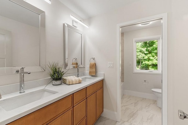 122 Charles St, Reading, MA 01867 - full bath with marble look tile flooring, double vanity, toilet, and baseboards