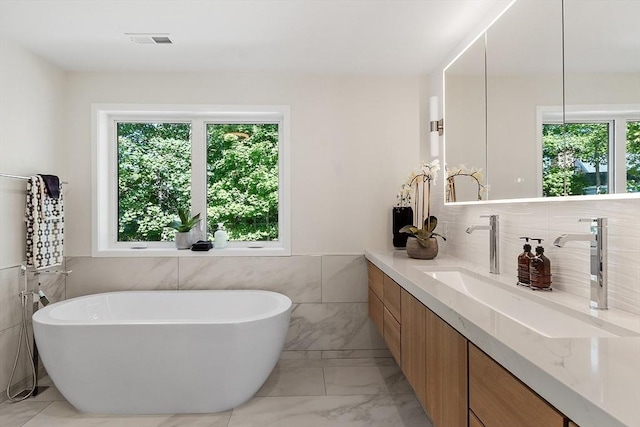 122 Charles St, Reading, MA 01867 - bathroom featuring tile walls, vanity, a soaking tub, marble look tiles, and a wainscoted wall