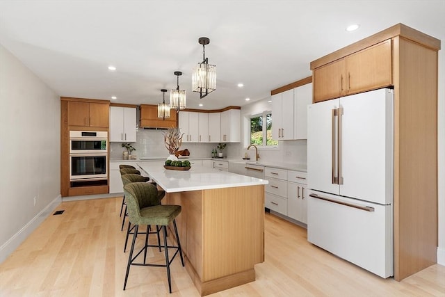 122 Charles St, Reading, MA 01867 - kitchen with freestanding refrigerator, stainless steel double oven, tasteful backsplash, recessed lighting, and light wood finished floors