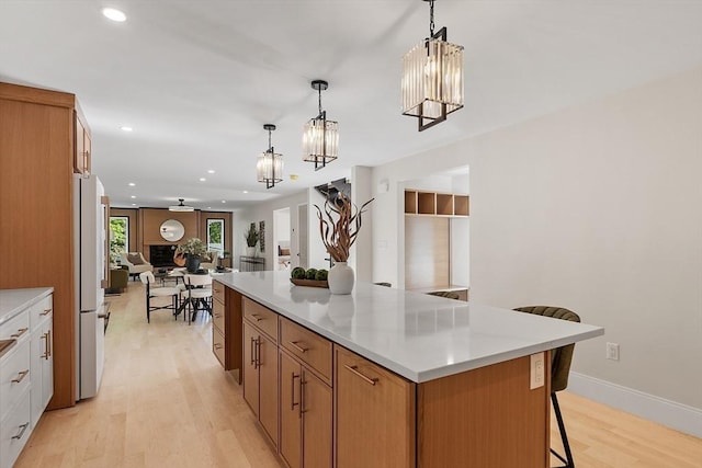 122 Charles St, Reading, MA 01867 - kitchen featuring open floor plan, light wood-style flooring, a kitchen breakfast bar, a chandelier, and recessed lighting