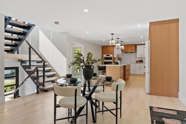 122 Charles St, Reading, MA 01867 - dining space featuring light wood finished floors, recessed lighting, stairway, and a chandelier