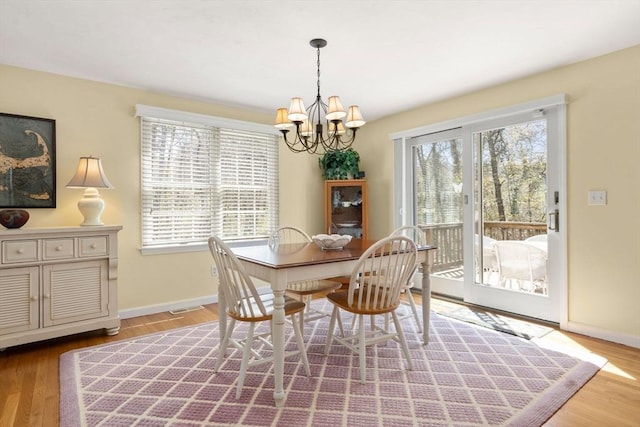 dining space with an inviting chandelier, baseboards, and wood finished floors