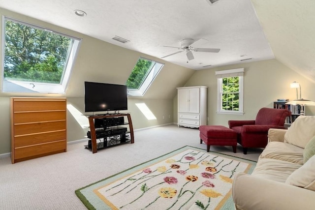 carpeted living area featuring baseboards, ceiling fan, lofted ceiling with skylight, and visible vents