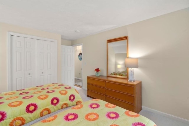 bedroom featuring baseboards, light carpet, and a closet