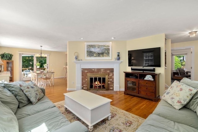 living room with a brick fireplace, recessed lighting, a wealth of natural light, and wood finished floors
