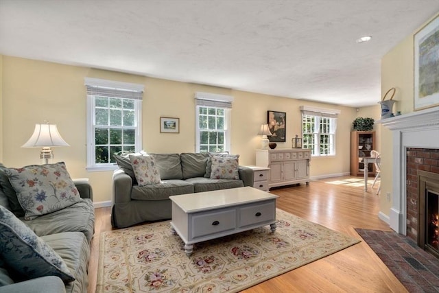 living area with baseboards, a brick fireplace, wood finished floors, and a wealth of natural light