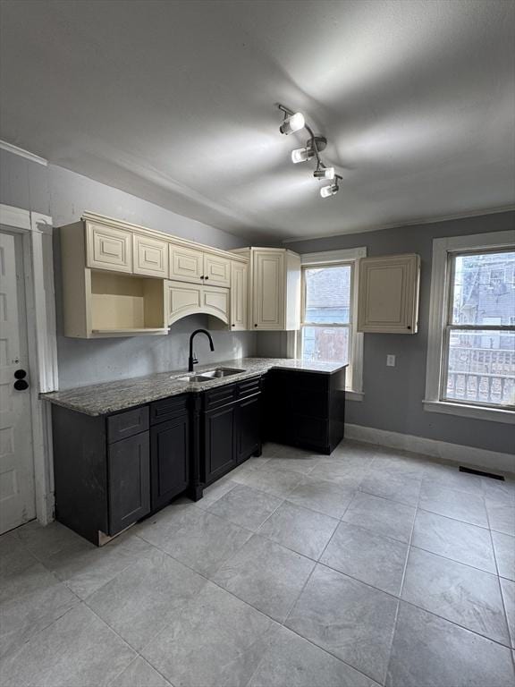 kitchen with cream cabinetry, light tile patterned floors, a healthy amount of sunlight, and sink