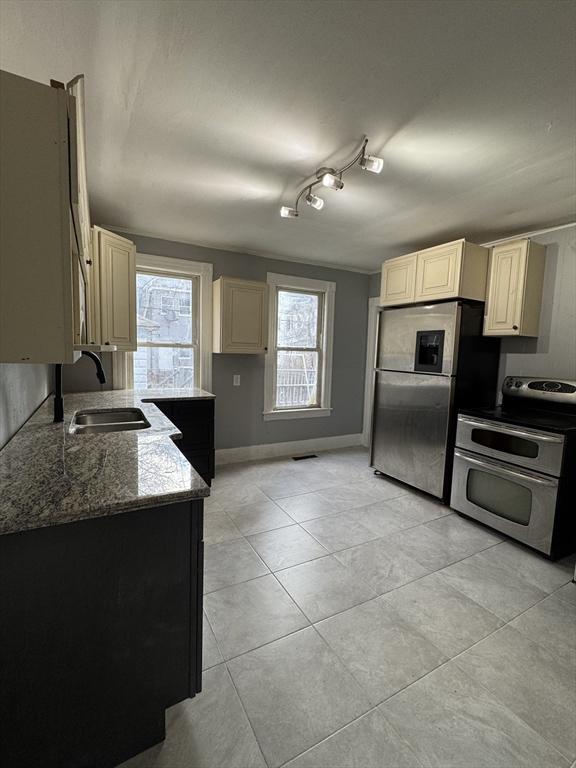 kitchen with appliances with stainless steel finishes, plenty of natural light, light stone counters, and sink