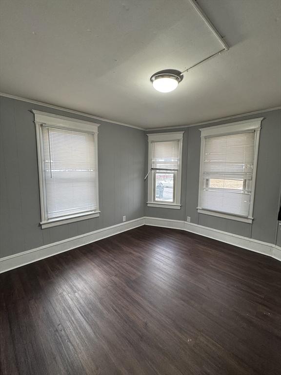 unfurnished room featuring ornamental molding and dark hardwood / wood-style floors