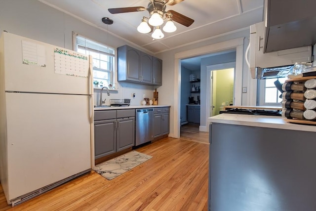 kitchen with freestanding refrigerator, gray cabinets, stainless steel dishwasher, light wood-style floors, and a sink