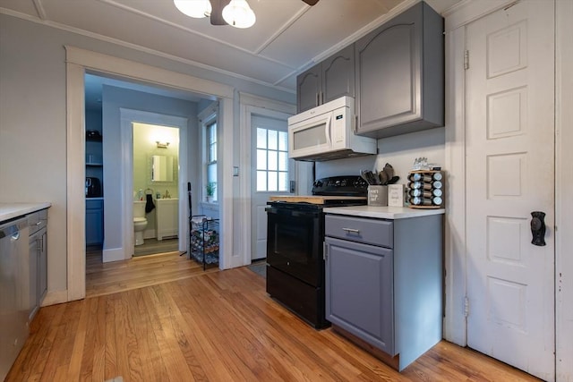 kitchen featuring light wood-style floors, gray cabinets, black electric range oven, and white microwave