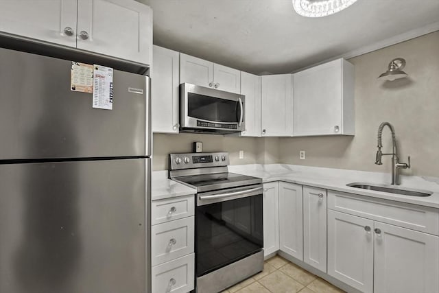 kitchen with sink, light stone countertops, light tile patterned floors, appliances with stainless steel finishes, and white cabinetry