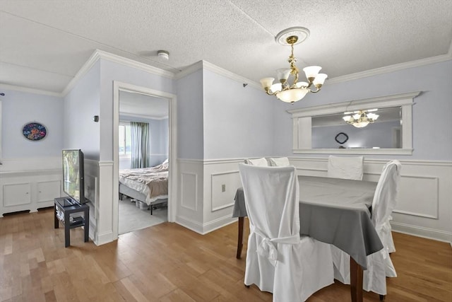 dining space with crown molding, light hardwood / wood-style floors, a textured ceiling, and an inviting chandelier