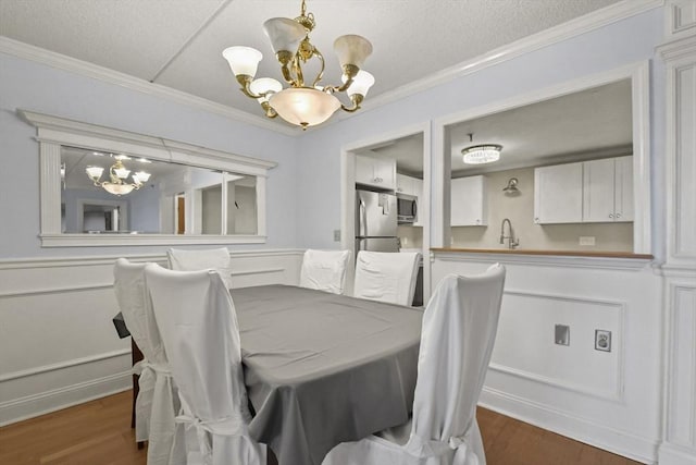 dining area featuring dark hardwood / wood-style flooring, ornamental molding, sink, and a chandelier