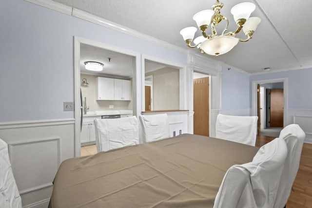 bedroom with crown molding, light hardwood / wood-style flooring, and an inviting chandelier