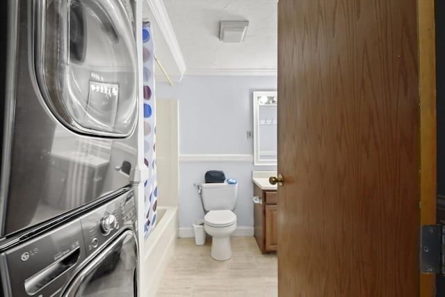 clothes washing area with crown molding and stacked washer / dryer