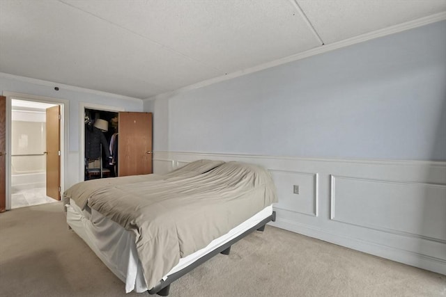 carpeted bedroom featuring ensuite bath and ornamental molding