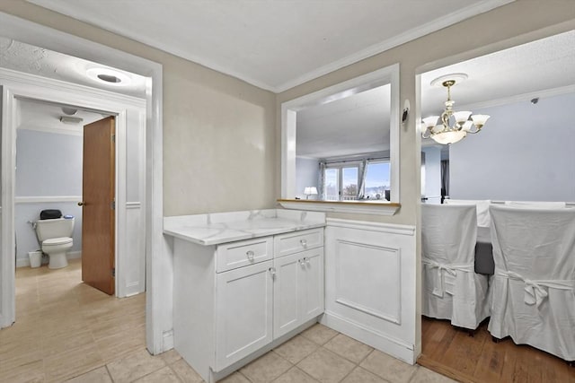 kitchen with white cabinetry, an inviting chandelier, pendant lighting, light tile patterned floors, and ornamental molding