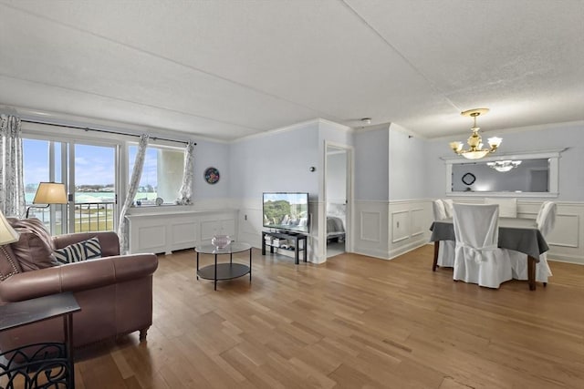 living room featuring wood-type flooring, an inviting chandelier, and crown molding