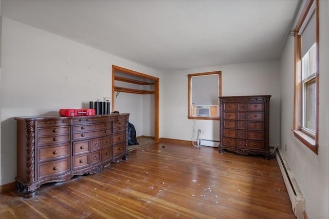 bedroom with cooling unit, dark hardwood / wood-style flooring, and baseboard heating