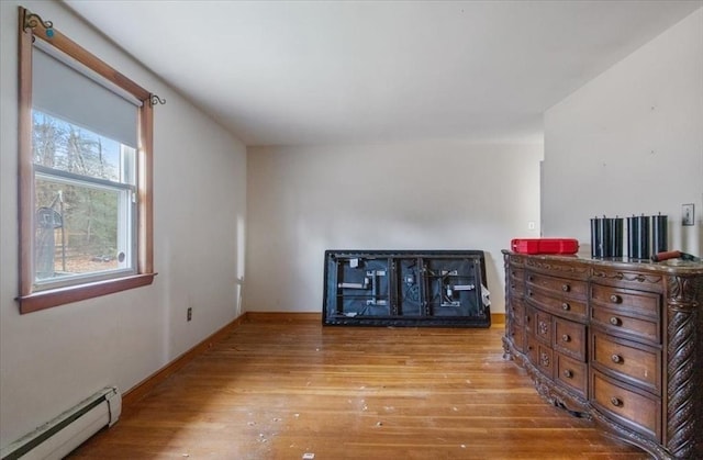 bedroom with light hardwood / wood-style floors and a baseboard heating unit