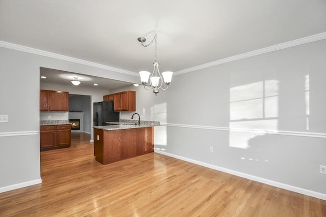 kitchen with hanging light fixtures, a notable chandelier, light hardwood / wood-style floors, black refrigerator, and sink