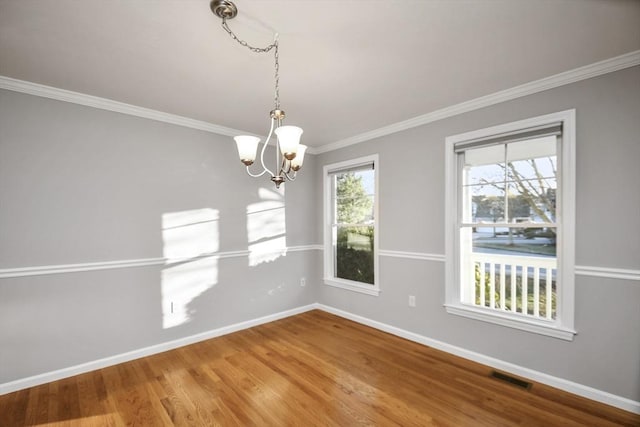 unfurnished dining area featuring an inviting chandelier, hardwood / wood-style flooring, and crown molding