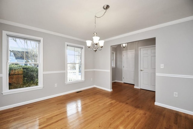 empty room featuring ornamental molding, hardwood / wood-style floors, and a chandelier