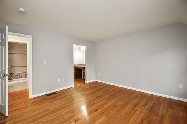 unfurnished bedroom featuring connected bathroom and light hardwood / wood-style floors