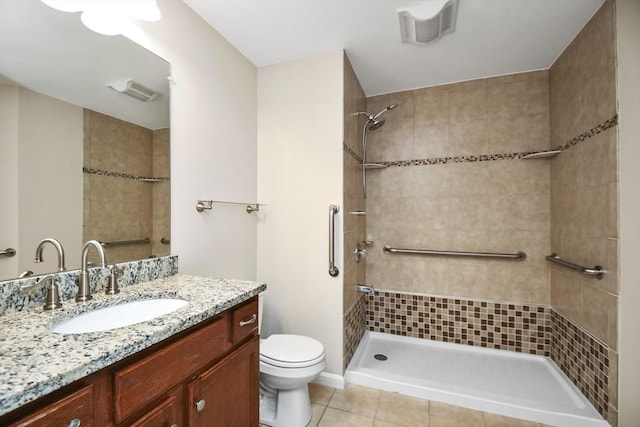 bathroom featuring toilet, tile patterned floors, tiled shower, and vanity