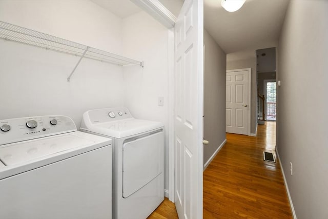 clothes washing area with hardwood / wood-style flooring and washer and clothes dryer