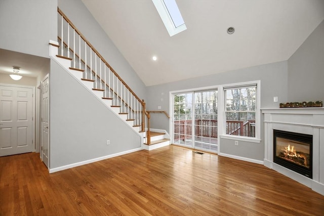 unfurnished living room featuring hardwood / wood-style floors and vaulted ceiling with skylight