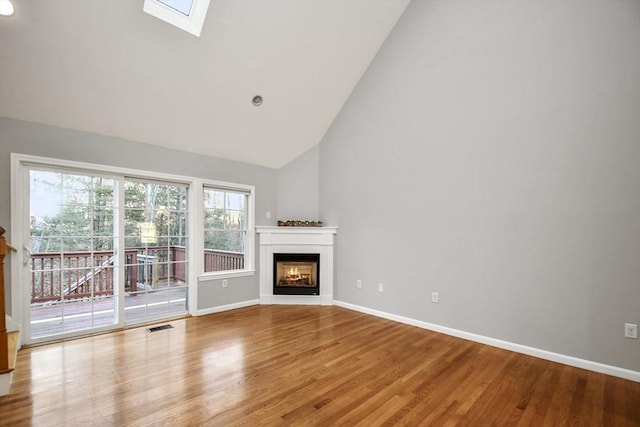 unfurnished living room with high vaulted ceiling, a skylight, and wood-type flooring