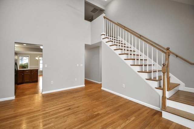 stairway with hardwood / wood-style flooring and a notable chandelier