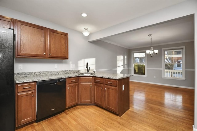 kitchen featuring black appliances, light hardwood / wood-style floors, a notable chandelier, light stone counters, and sink