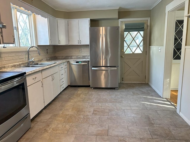 kitchen featuring appliances with stainless steel finishes, a sink, light countertops, white cabinetry, and a wealth of natural light