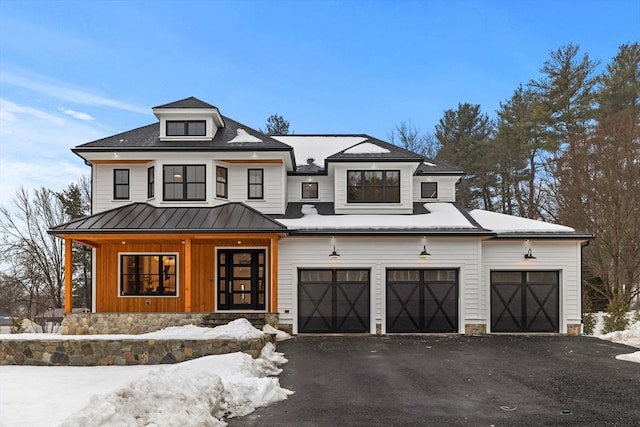 view of front of house with a standing seam roof, aphalt driveway, and metal roof