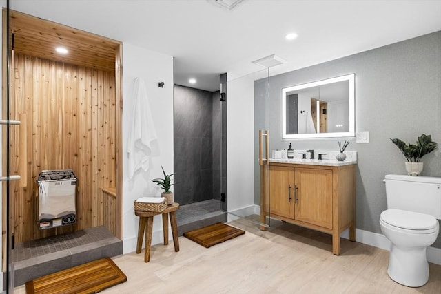 full bathroom with vanity, wood finished floors, tiled shower, recessed lighting, and toilet