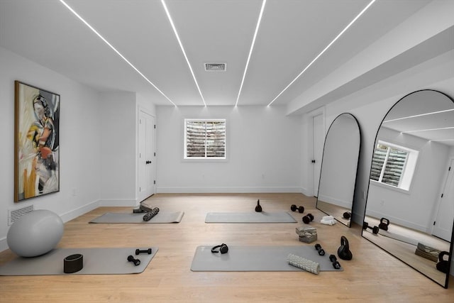 exercise area with visible vents, baseboards, and wood finished floors