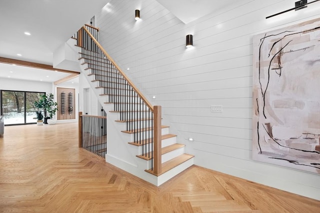 staircase with recessed lighting, baseboards, and wood walls