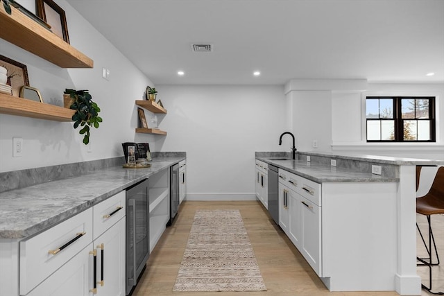 kitchen with visible vents, beverage cooler, a breakfast bar, white cabinets, and open shelves