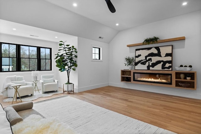 living room featuring visible vents, baseboards, recessed lighting, wood finished floors, and a glass covered fireplace