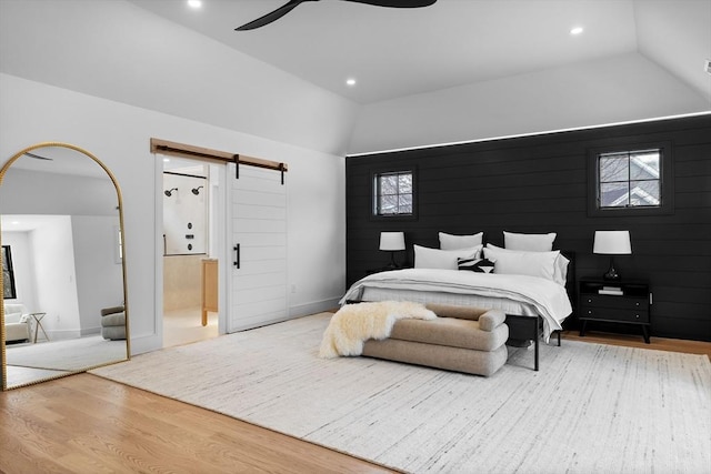 bedroom with a barn door, recessed lighting, wood finished floors, and lofted ceiling