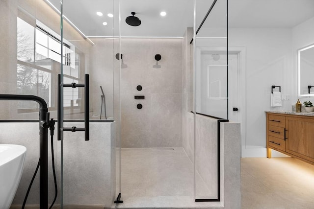 bathroom with a walk in shower, vanity, and a freestanding tub