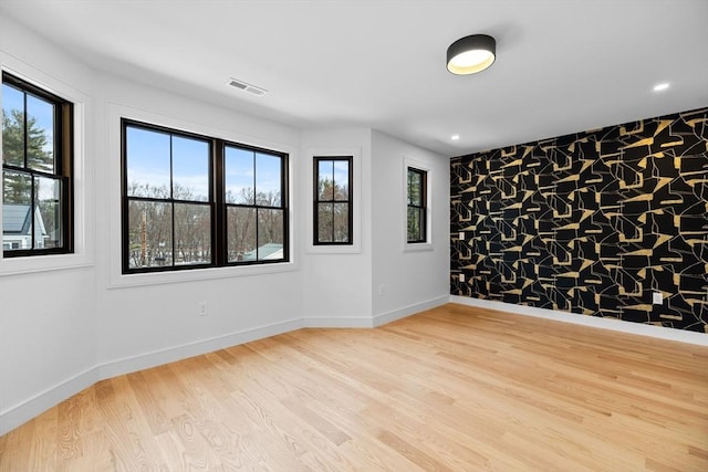 spare room featuring wood finished floors, baseboards, and a healthy amount of sunlight