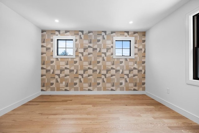 unfurnished room featuring baseboards, plenty of natural light, and wood finished floors