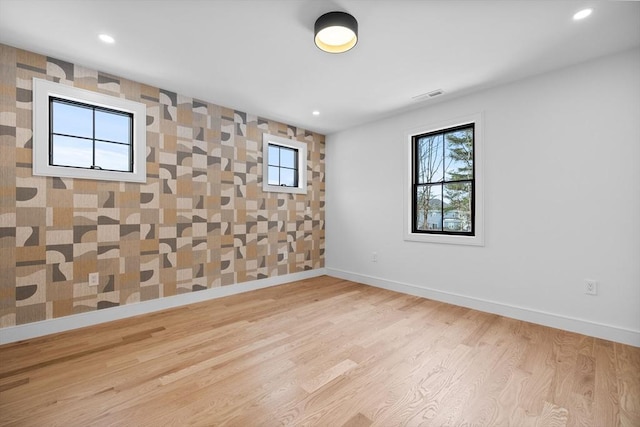 empty room with recessed lighting, wood finished floors, visible vents, and baseboards